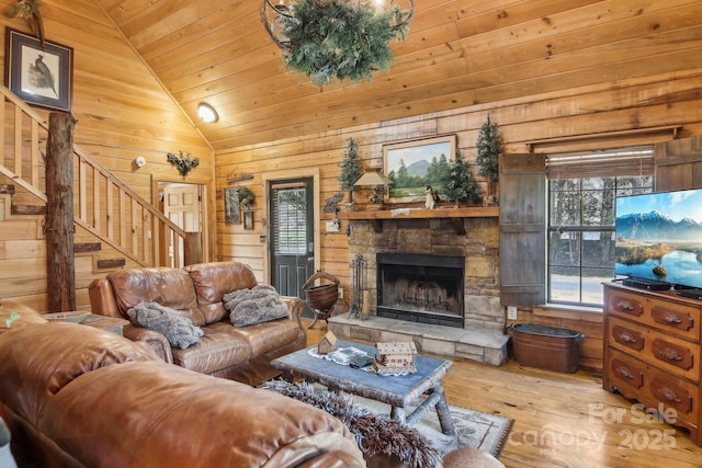 living room featuring lofted ceiling, wood ceiling, wood walls, hardwood / wood-style floors, and stairs