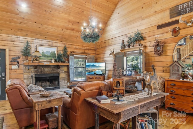 living room featuring a notable chandelier, a stone fireplace, wood finished floors, high vaulted ceiling, and stairs