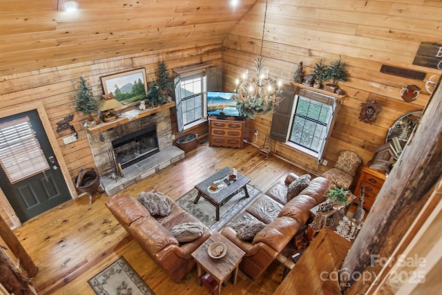 living room featuring lofted ceiling, a fireplace, hardwood / wood-style floors, and an inviting chandelier