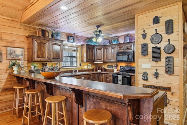 kitchen featuring a ceiling fan, a sink, wooden ceiling, a peninsula, and black appliances