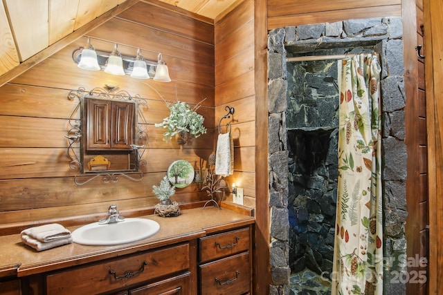 full bathroom with a stall shower, vanity, and wooden walls