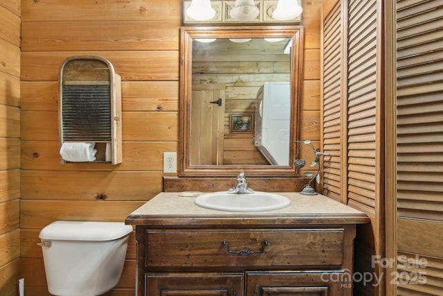 half bathroom with wood walls, vanity, and toilet