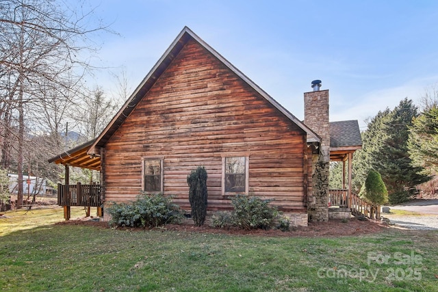 view of side of home featuring roof with shingles, a yard, and a chimney