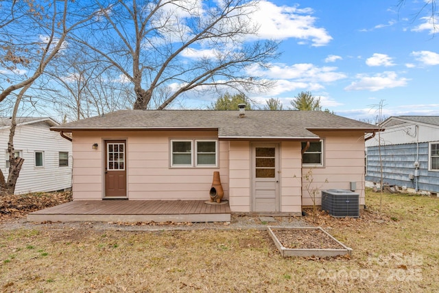 back of house featuring roof with shingles, a vegetable garden, a yard, a deck, and central air condition unit