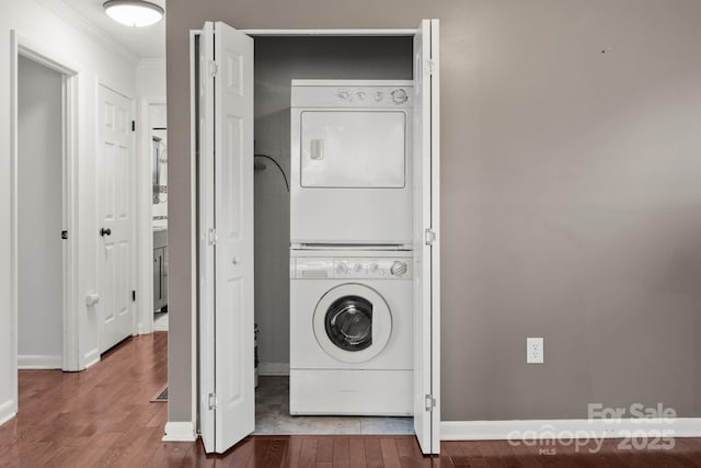 laundry room with laundry area, wood finished floors, stacked washer / drying machine, and ornamental molding