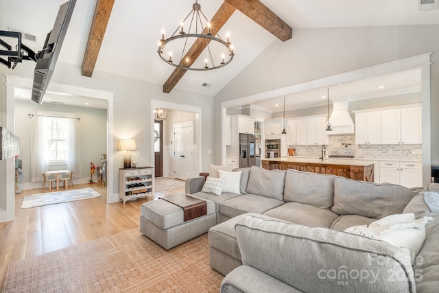 living room with baseboards, a chandelier, beamed ceiling, light wood-type flooring, and high vaulted ceiling