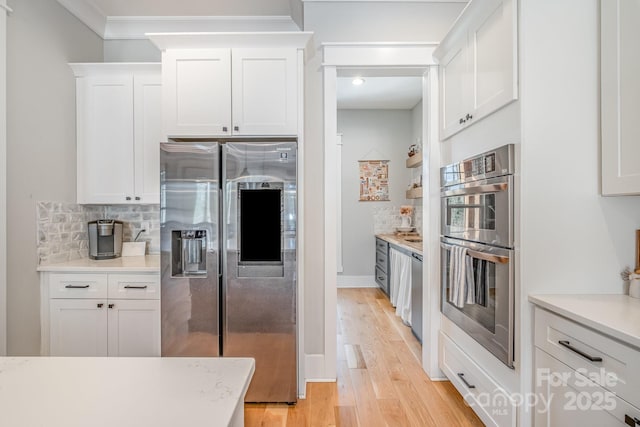 kitchen with light wood-type flooring, white cabinetry, appliances with stainless steel finishes, and decorative backsplash