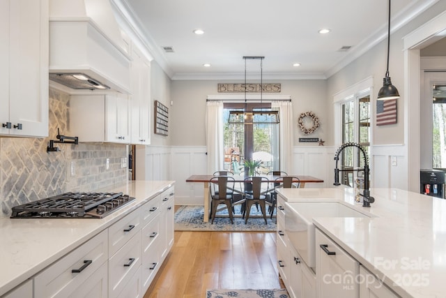 kitchen featuring visible vents, custom range hood, ornamental molding, light wood-type flooring, and gas cooktop