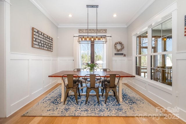 dining area with ornamental molding, recessed lighting, light wood-style floors, and a decorative wall