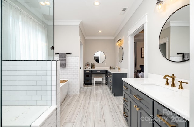 bathroom with tiled bath, two vanities, a sink, and visible vents