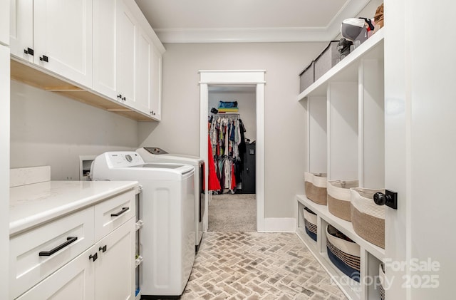 clothes washing area featuring brick floor, cabinet space, ornamental molding, separate washer and dryer, and baseboards