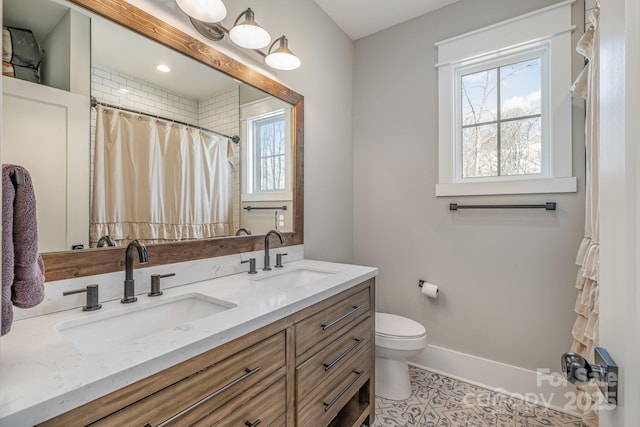 full bathroom with double vanity, a sink, and a wealth of natural light