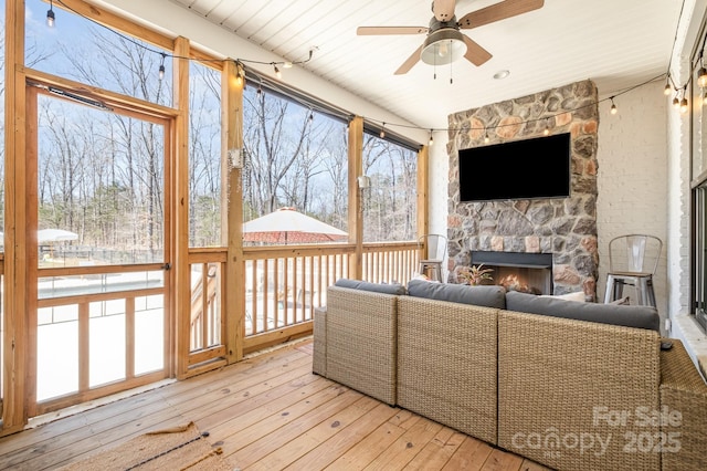 sunroom featuring a fireplace and a ceiling fan