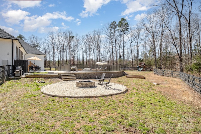 view of yard featuring playground community, a patio, a fire pit, and a fenced backyard