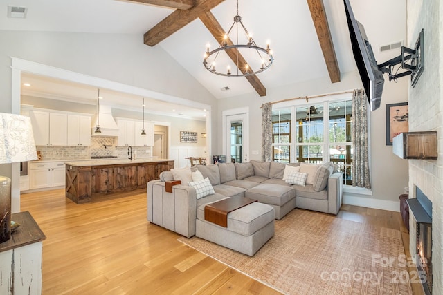 living room featuring visible vents, a large fireplace, high vaulted ceiling, light wood-type flooring, and beamed ceiling