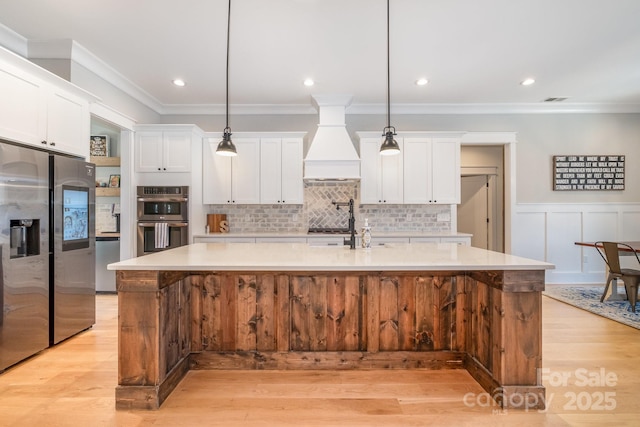 kitchen with light countertops, appliances with stainless steel finishes, a spacious island, and white cabinets