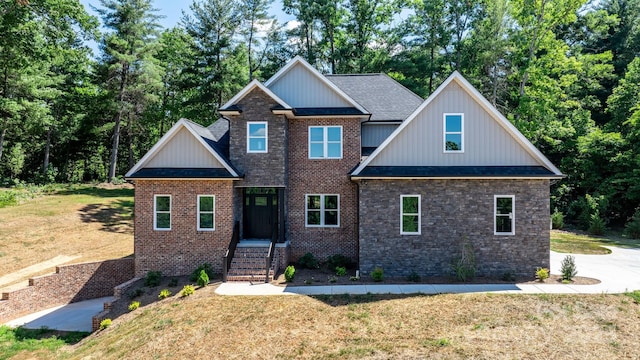 craftsman house featuring brick siding, board and batten siding, a front yard, and a shingled roof