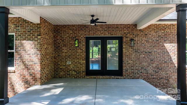 entrance to property featuring board and batten siding, french doors, brick siding, and ceiling fan