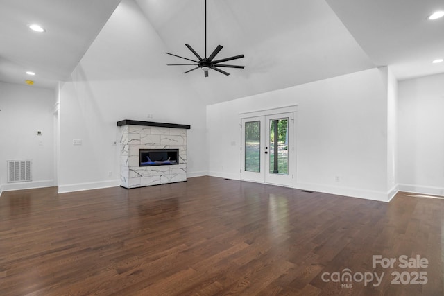 unfurnished living room featuring ceiling fan, a premium fireplace, wood finished floors, visible vents, and french doors