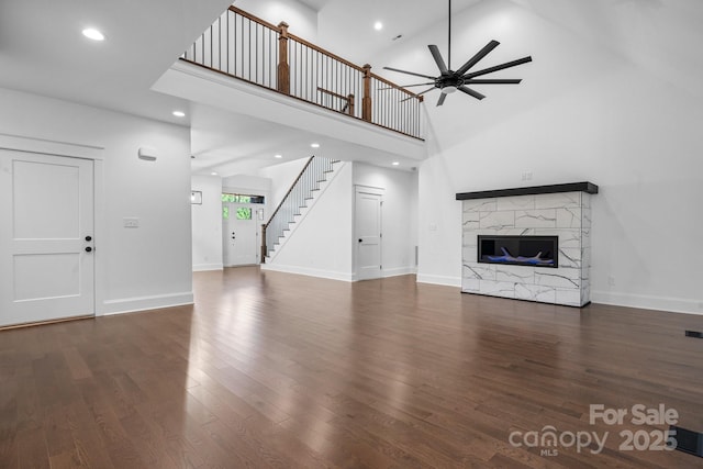 unfurnished living room featuring stairway, a premium fireplace, wood finished floors, and baseboards