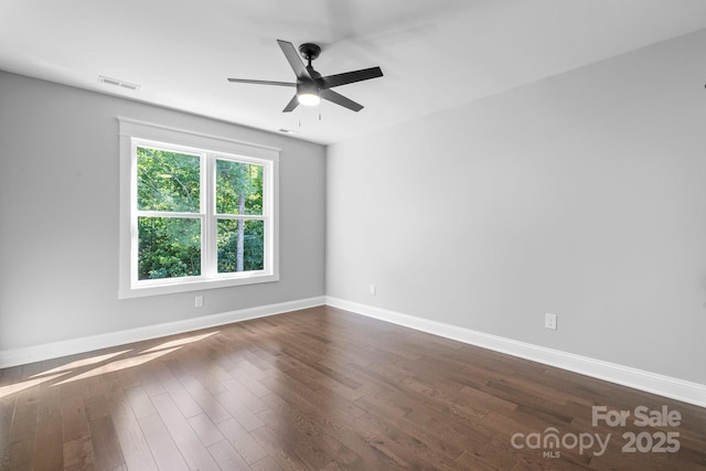 unfurnished room featuring dark wood-type flooring, visible vents, baseboards, and a ceiling fan