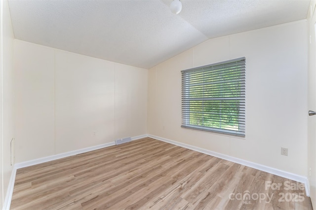 843 Deep Gap Loop Rd, Flat Rock, NC 28731 - unfurnished room with light wood finished floors, lofted ceiling, a textured ceiling, and baseboards