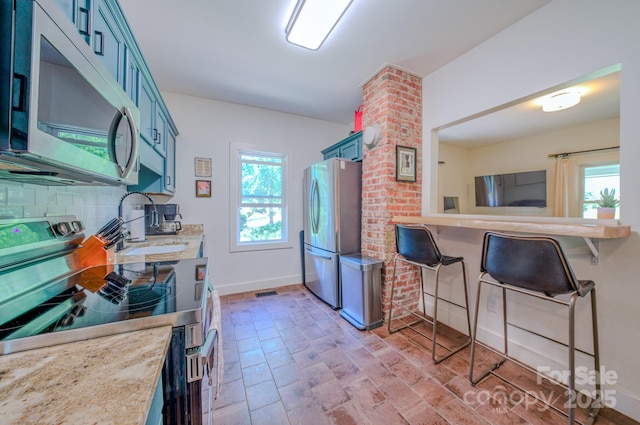 124 Dodge St, Asheville, NC 28803 - kitchen featuring appliances with stainless steel finishes, blue cabinetry, a sink, decorative backsplash, and baseboards
