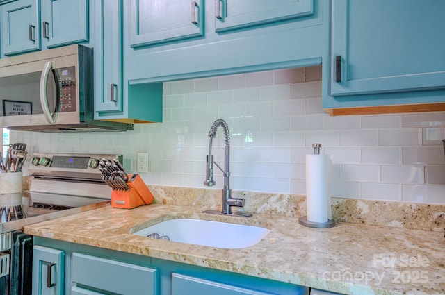 124 Dodge St, Asheville, NC 28803 - kitchen with stainless steel appliances, a sink, blue cabinets, and decorative backsplash