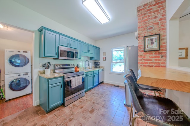 124 Dodge St, Asheville, NC 28803 - kitchen featuring stainless steel appliances, stacked washer / drying machine, a sink, blue cabinets, and light countertops