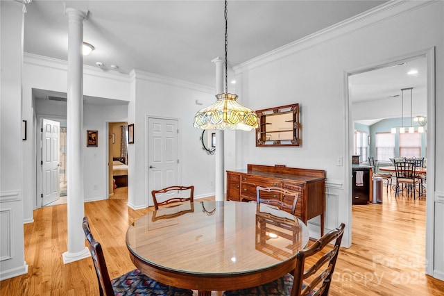 dining room featuring light wood-style floors, ornamental molding, and ornate columns