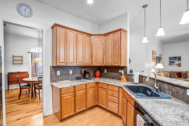 kitchen featuring light wood-style flooring, light stone countertops, tasteful backsplash, and a sink