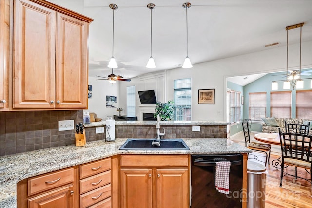 kitchen with a sink, light stone counters, black dishwasher, open floor plan, and a peninsula