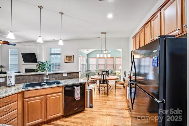 kitchen featuring ceiling fan, black appliances, open floor plan, and a sink