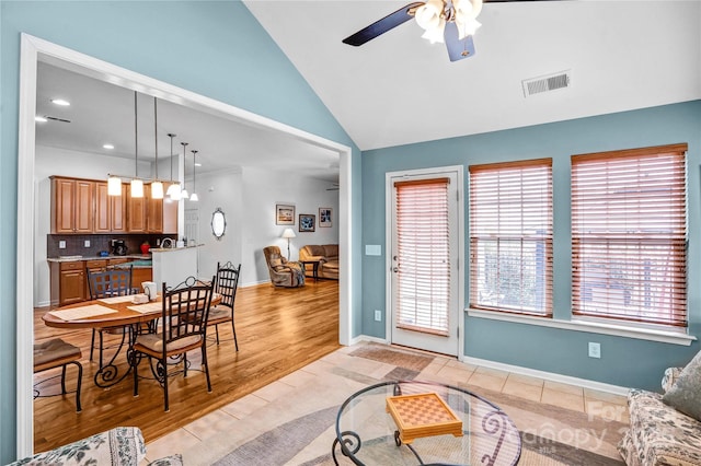 living area featuring light wood-type flooring, visible vents, baseboards, ceiling fan, and vaulted ceiling