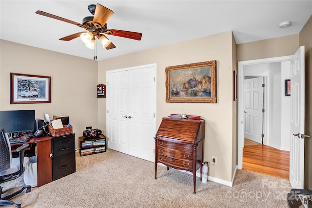 home office featuring light carpet, ceiling fan, and baseboards