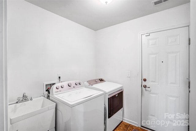 clothes washing area with washer and clothes dryer, laundry area, visible vents, and a sink