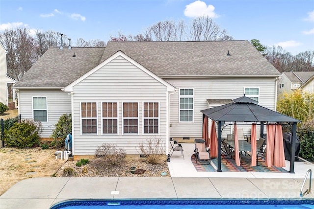 rear view of property featuring a patio, roof with shingles, an outdoor pool, a gazebo, and crawl space