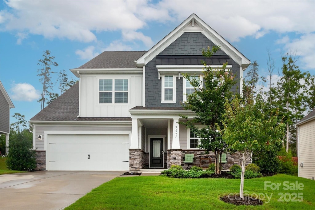 craftsman-style home featuring an attached garage, driveway, stone siding, board and batten siding, and a front yard