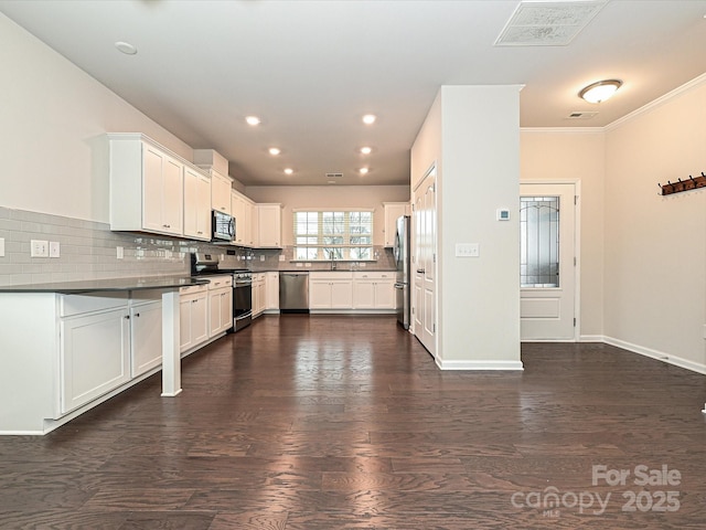 kitchen featuring dark wood-style floors, tasteful backsplash, dark countertops, visible vents, and appliances with stainless steel finishes