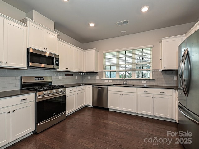 kitchen featuring dark countertops, visible vents, stainless steel appliances, and a sink