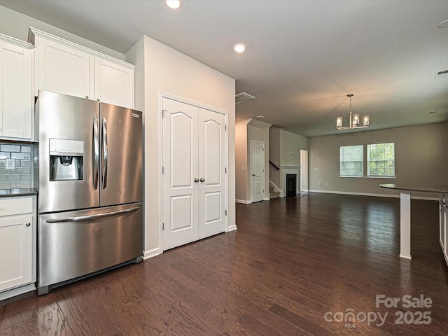 kitchen featuring tasteful backsplash, white cabinets, stainless steel fridge with ice dispenser, dark wood-type flooring, and a notable chandelier