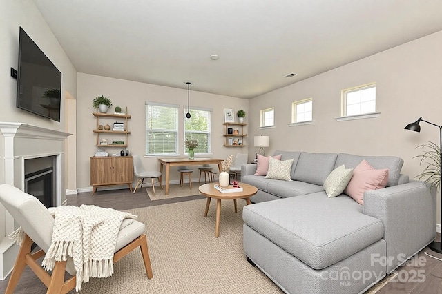 living area with a glass covered fireplace, visible vents, and baseboards