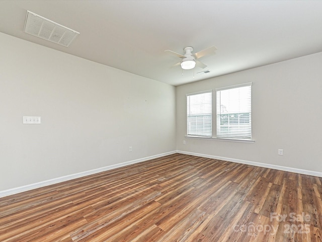 spare room featuring baseboards, visible vents, and wood finished floors