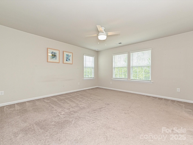 spare room with carpet floors, visible vents, baseboards, and a ceiling fan