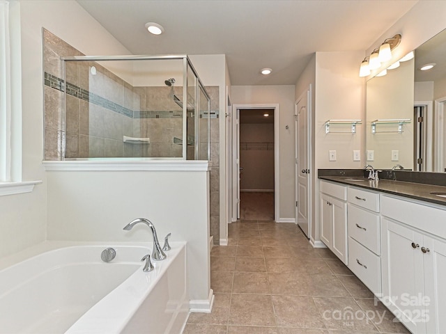 full bathroom featuring a spacious closet, a stall shower, vanity, a bath, and tile patterned floors