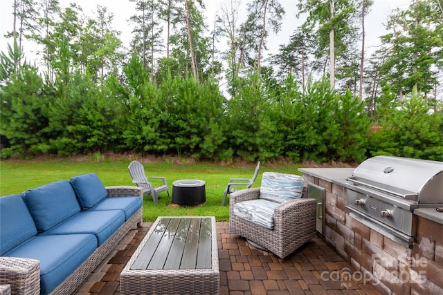 view of patio with area for grilling and an outdoor living space with a fire pit