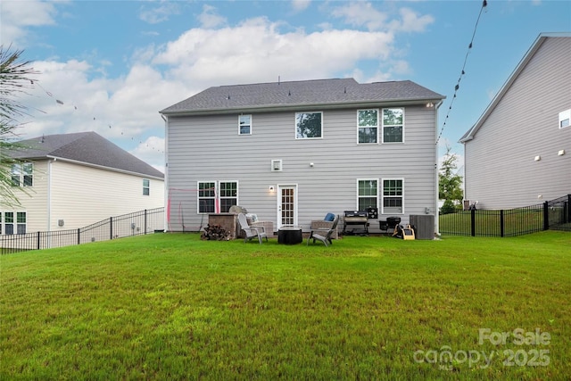 back of property with a fenced backyard, central AC, and a lawn