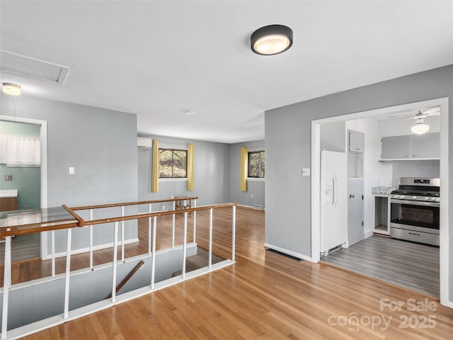 unfurnished room featuring light wood-style floors, visible vents, baseboards, and a wall mounted AC