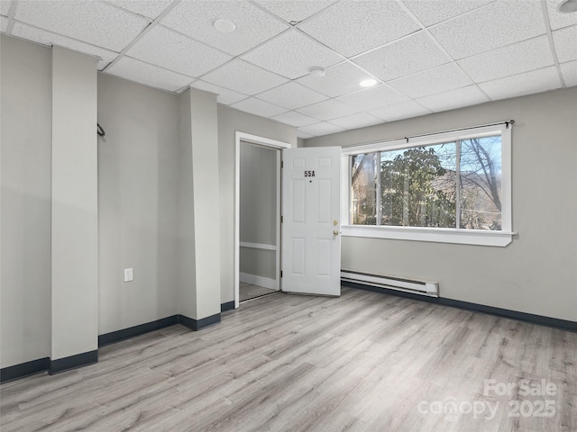 spare room with a baseboard radiator, baseboards, and wood finished floors