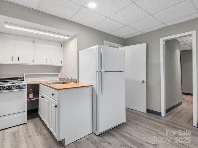 kitchen with light wood-type flooring, white appliances, white cabinets, and a sink